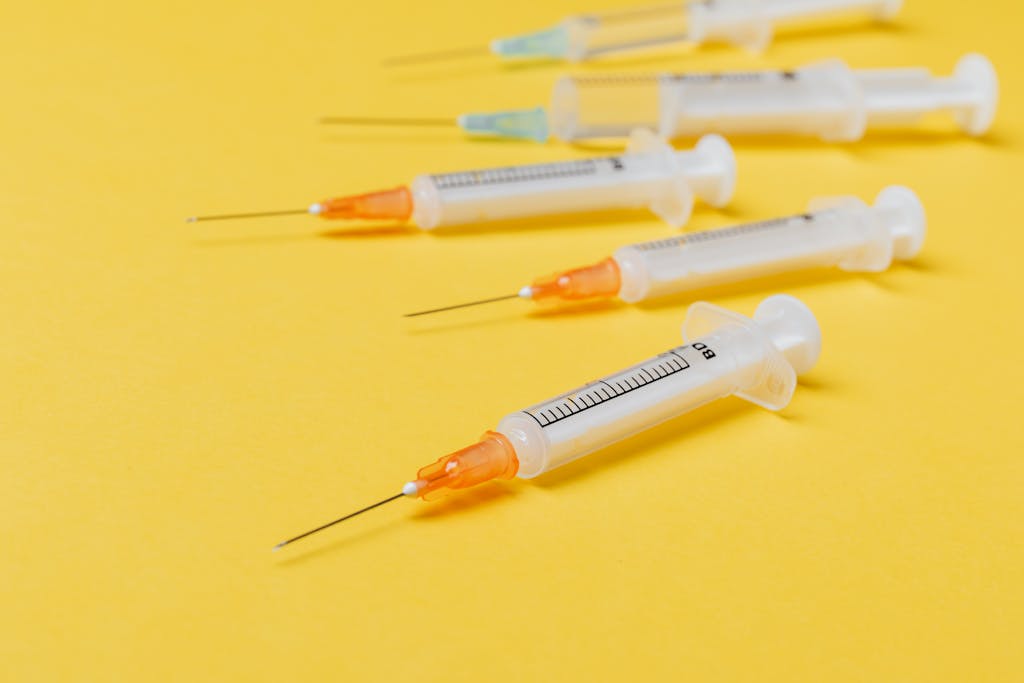 Close-up of sterile disposable syringes on a vibrant yellow surface.